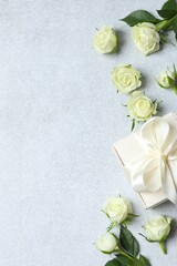 Beautiful white roses with gift box on grey background