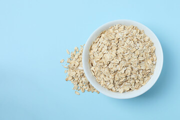 Composition with oatmeal flakes on blue background. Cooking breakfast