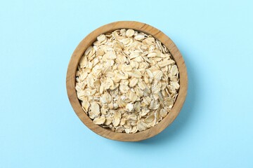 Composition with oatmeal flakes on blue background. Cooking breakfast