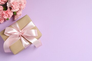 Beautiful bouquet of pink carnations with gift box on color background
