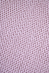 light pink texture of knitted wool fabric as a background, smooth symmetrical lines of hand-knitted...