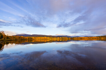 Autumn landscape of Northern Norway, with colorful trees, serene water reflections, and dramatic mountains.
