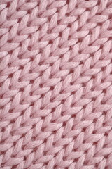 light pink texture of knitted wool fabric as a background, smooth symmetrical lines of hand-knitted needlework pattern	
