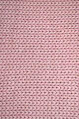 light pink texture of knitted wool fabric as a background, smooth symmetrical lines of hand-knitted needlework pattern	
