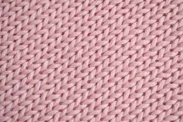 light pink texture of knitted wool fabric as a background, smooth symmetrical lines of hand-knitted needlework pattern	
