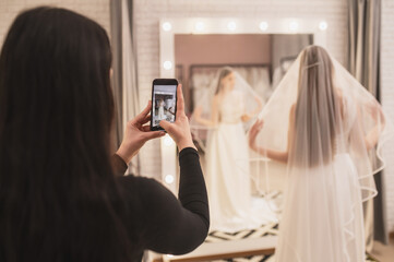 Bride tries on dress in wedding salon with consultant.
 veil and dress wedding boutique
Blogger...