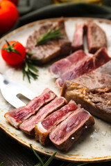 Pieces of delicious beef meat, spices and tomato on table, closeup