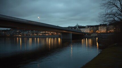 A concrete bridge reflects lights from a nearby city at twilight