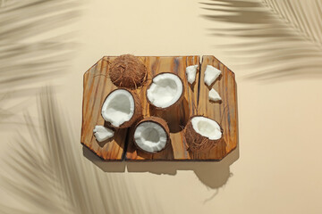Fresh coconuts and shadow cast by tropical palm on beige background, above view