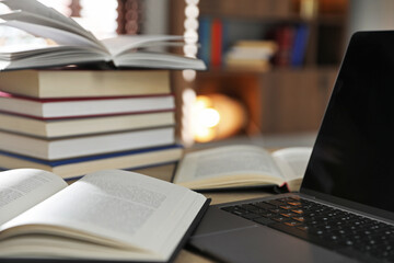 Many books and laptop on table indoors, closeup