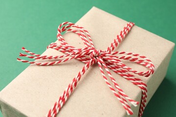 Gift wrapped in kraft paper with bow on green background, closeup