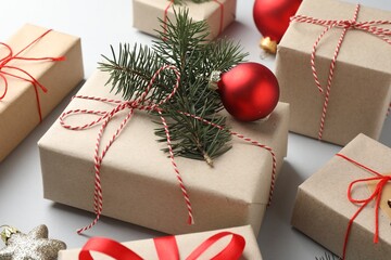 Gifts wrapped in kraft paper with Christmas decor on light background, closeup