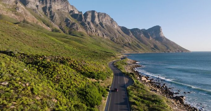 Spectacular aerial view of a winding road next to unspoilt beaches and a majestic mountain range in Cape Town&rsquo;s stunning coastal landscape, popular tourist destination in South Africa