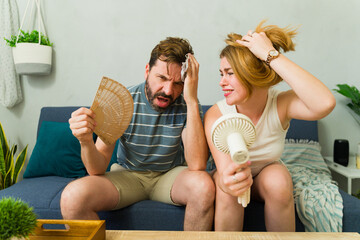 Couple sweating and suffering from summer heat wave at home