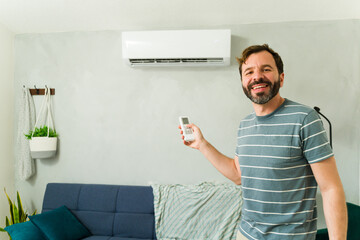 Portrait of a man smiling and turning on air conditioning during summer heatwave
