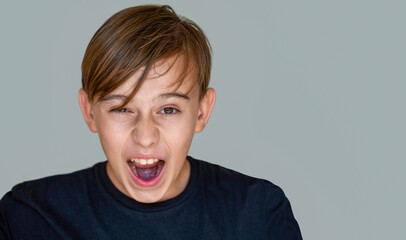 Young man screaming, isolated gray background. Scream. Child with angry expression. Shocked panic kid boy, screaming in despair, frustration.Young angry boy yelling