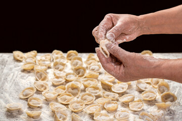 Hands, ravioli, meat filling. Woman making meaty ravioli. Chef cook hands making handmade Tortellini ravioli on table with flour