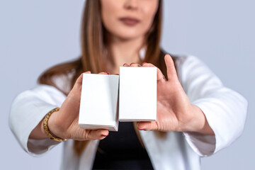 Female shop assistant with cardboard package at work. Doctor's hands hold boxes with medical preparations. Doctor hand showing drug boxes. Pharmacist showing white blank medicine box with pharmacy