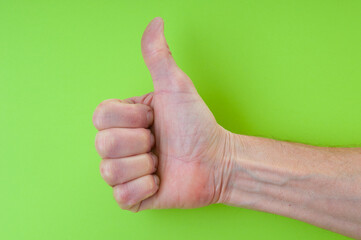 Hand thumb up gesture close up  on green background
