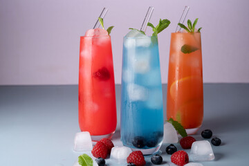 vibrant trio of refreshing summer beverages in tall glasses with fresh fruits and mint garnish against soft pastel backdrop for a cool and inviting atmosphere, zest, hydrate, vitality, clear, peach
