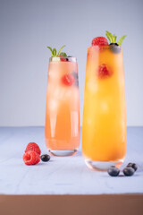 Fototapeta premium refreshing assorted fruit beverages with berries and mint in tall glasses on a minimalistic light blue surface with soft lighting, cooling, garnish, layered, inviting, sweet, fresh, elegant