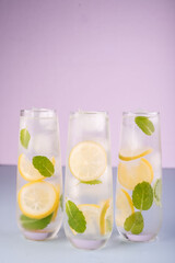 refreshing trio of lemon and mint infused water glasses against pastel lavender background for a cool and inviting summer beverage aesthetic, bright, crisp, colorful, clean, cold, pure, detox