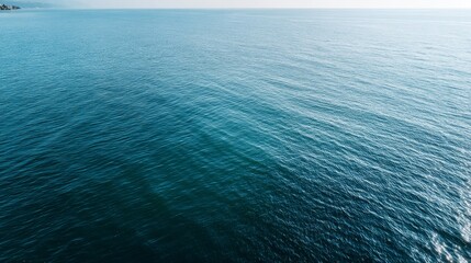 Fototapeta premium Experience the tranquility of a deep azure ocean surface showcasing gentle ripples and variations in shade, complemented by clear copy space for creative use