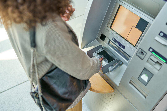 Businesswoman making a contactless payment using smartphone at an atm to withdraw cash, showcasing modern banking technology and convenience