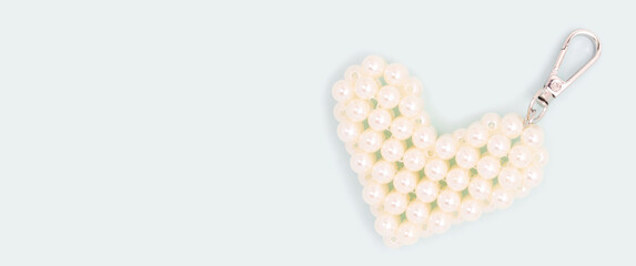 Banner with keychain in a heart shape made from pearl beads on a blue background. Place for text.