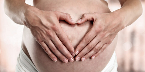 Close-up of pregnant woman's hands gently placed on her baby bump, expressing maternal love. Tender...