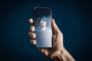 Deep fake or face recognition. AI deepfake or identity verification with phone. Scam, fraud or theft security. ID scan from eye. Man and biometric mobile protection concept. Smartphone in hand.