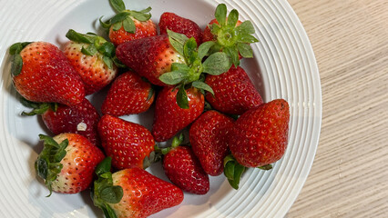 Fresh ripe strawberries on a white plate, symbolizing summer harvest and delicious treats, perfect for a healthy snack