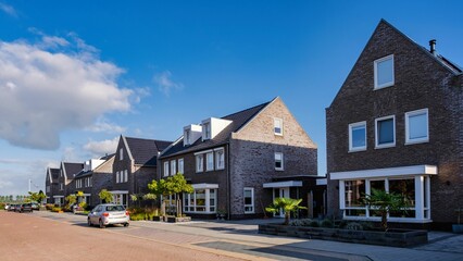 Fototapeta na wymiar Modern family houses in a serene Dutch suburban neighborhood under clear blue skies