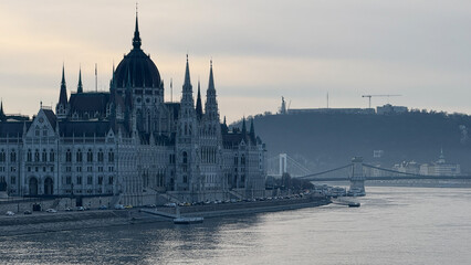 Naklejka premium Majestic view of the Budapest Parliament by the Danube River, capturing European architecture and travel inspiration, perfect for holiday postcards