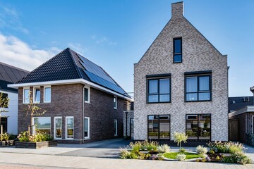 Modern houses featuring solar panels against a clear blue sky in a sustainable neighborhood