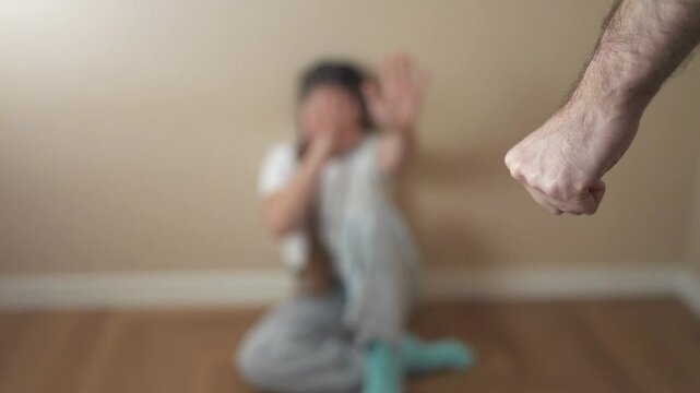Person sitting on the floor with their hand up. A child is threatening to punch a girl with a fist. A girl is afraid of danger. An individual seated on the ground with their hand lifestyle raised.