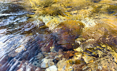 dynamic clear water surface. assorted stones under rippling water. natural texture, abstract nature background. stone background. artistic backdrop with clean