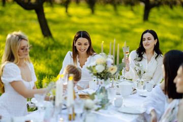 A gathering of women is seated around a table set in a beautiful field