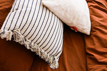 Cozy neutral pillows on a warm brown bedding in a peaceful indoor setting
