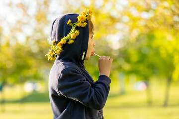 Portrait of cute stylish smiling toddler boy sitting in the grass in park
