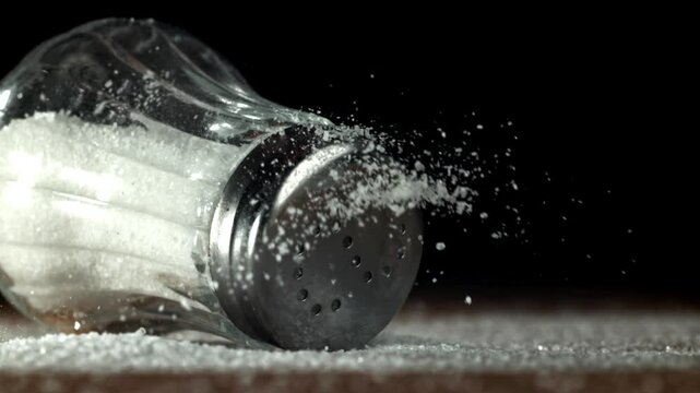 A salt shaker falls on a wooden table. Filmed on a high-speed camera at 1000 fps. High quality FullHD footage