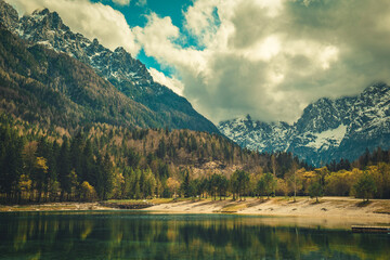 A tranquil scene from Kranjska Gora, Slovenia, featuring a crystal clear turquoise lake in the foreground.