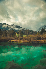 A tranquil scene from Kranjska Gora, Slovenia, featuring a crystal clear turquoise lake in the foreground.