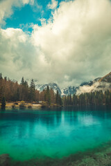 A tranquil scene from Kranjska Gora, Slovenia, featuring a crystal clear turquoise lake in the foreground.