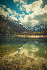 A tranquil scene from Kranjska Gora, Slovenia, featuring a crystal clear turquoise lake in the foreground.