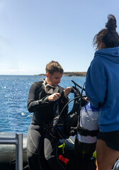 Diver preparing equipment on boat with divemaster assistance before scuba diving