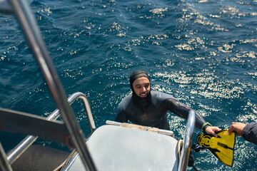 Diver getting ready to dive from boat with flippers assistance