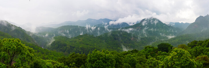 Mountains pierce the sky, wrapped in drifting clouds. Mist dances across ridges, veiling peaks in...