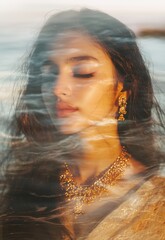 A double exposure of an Indian woman with long hair and eyes closed. The background is blurred, creating soft edges around the images.