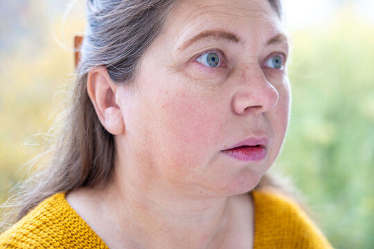 middle-aged mature woman with bulging eyes, face close-up, goggle eyes in fright, startled and scared expression, intense reaction conveying shock and fear